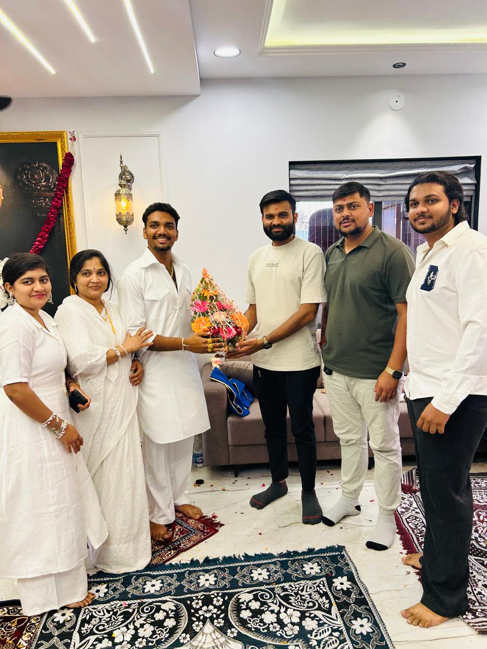 Sarvamangal team and a family holding a celebratory bouquet in their home